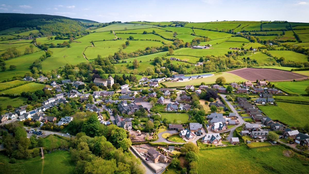 Aerial view above houses in an old British village in the countryside. Warm colours give a homely effect.